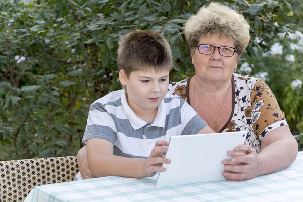 Granny with grandson watching tablet in nature — Stock Photo, Image