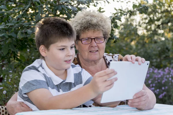 Oma mit Enkel schaut Tablet in der Natur — Stockfoto