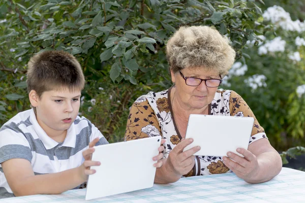 Babička s vnukem sledování tabletu v přírodě — Stock fotografie