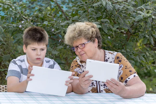 Mamie avec petit-fils regarder la tablette dans la nature — Photo