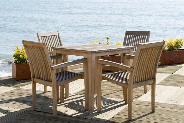 Кафе с деревянными столами и стульями на берегу моря — стоковое фото