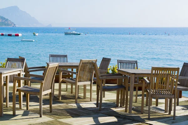 Cafe met houten tafels en stoelen op zee — Stockfoto