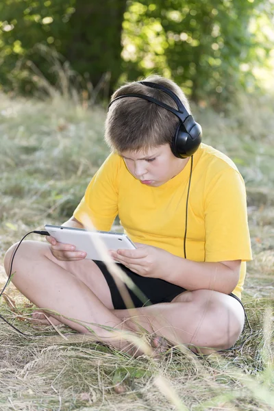 Boy v sluchátka tabletový počítač při pohledu na přírodu — Stock fotografie