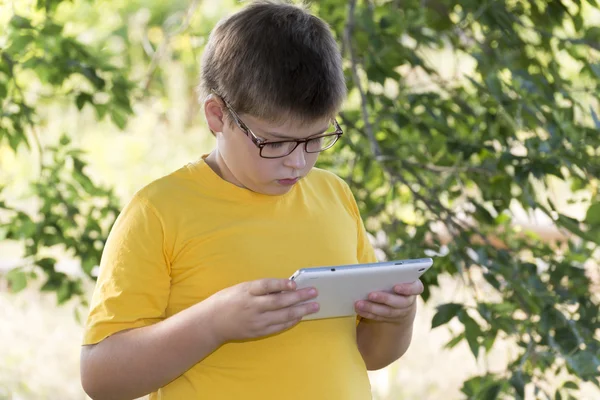 Gözlüklü çocuk tablet bilgisayar doğa görünüyor. — Stok fotoğraf