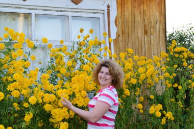 Orta yaşlı kadın evin yanında çiçek bakmakta