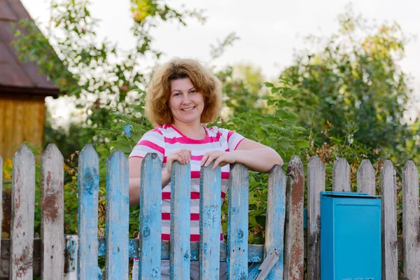 Donna di mezza età si trova al cancello casa di campagna — Foto Stock