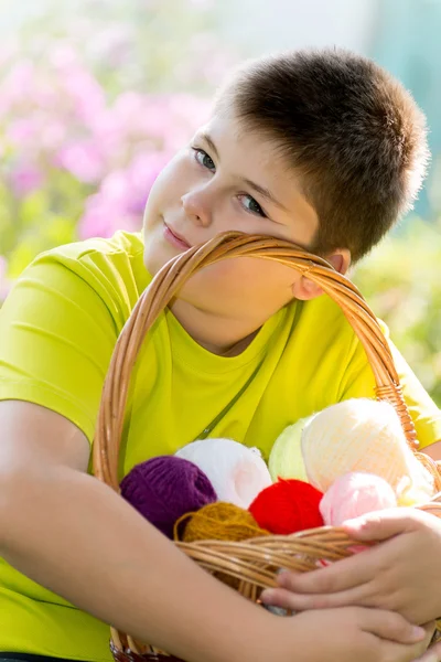 Tiener jongen met rieten mand en ballen van garen — Stockfoto