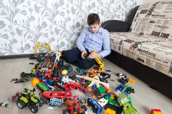 Мальчик-подросток играет с игрушечными машинами в комнате — стоковое фото