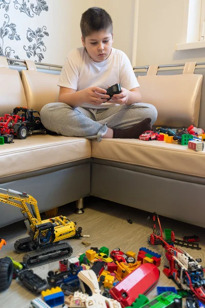 Мальчик-подросток играет с игрушечными машинами в комнате — стоковое фото