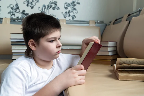 Tonåring pojke läser en bok i rum — Stockfoto