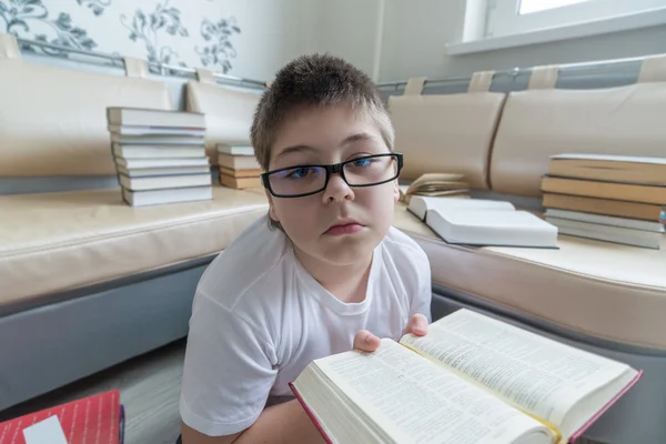Chłopiec w okularach, czytanie książki w pokoju — Zdjęcie stockowe