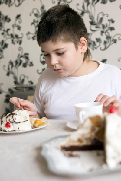 Boy drinks tea with cake at  table — Stock Photo, Image