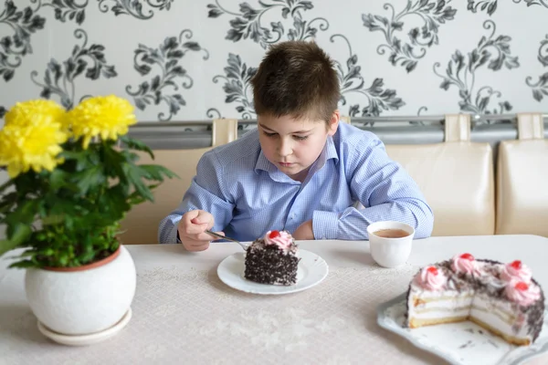 Мальчик ест торт за столом — стоковое фото
