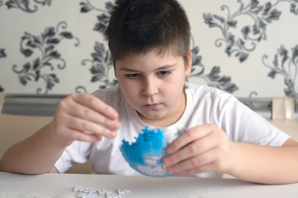 Teenager boy collects puzzles from Globe — Stock Photo, Image