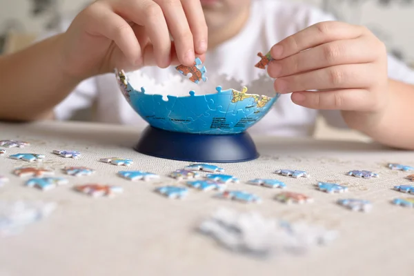 Jongen verzamelt puzzels van Globe — Stockfoto