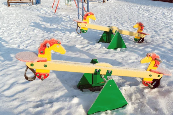 Balançoire couverte de neige et glissière à l'aire de jeux en hiver — Photo