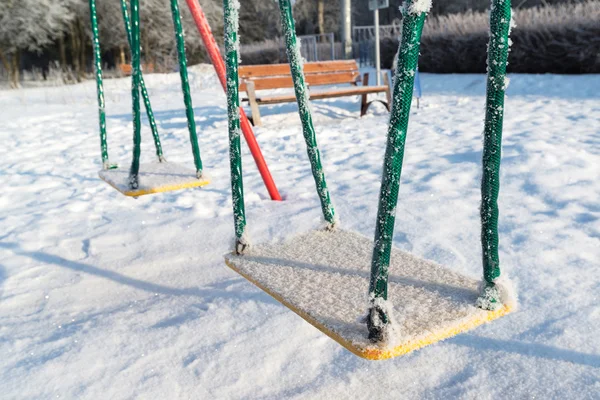 雪在冬天盖秋千和滑梯在操场上 — 图库照片