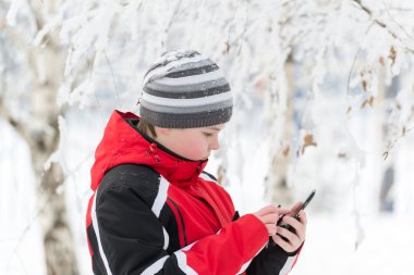 Genç çocuk sms kış parkta yazıyor.