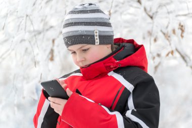Genç çocuk sms kış parkta yazıyor.