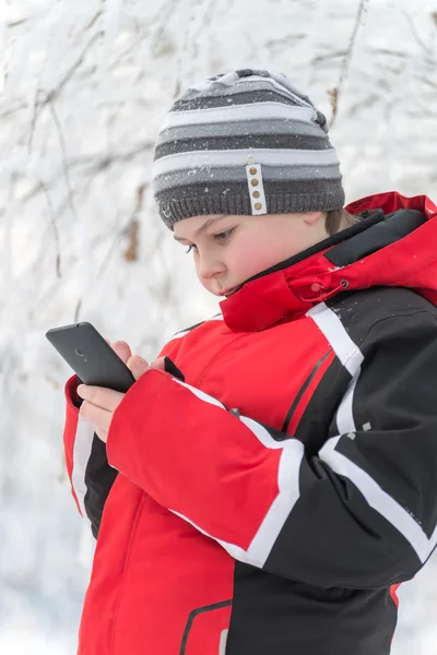 Teenager boy writes sms in winter park — Stock Photo, Image