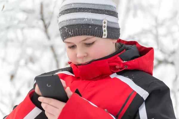 Teenager boy writes sms in winter park — Stock Photo, Image