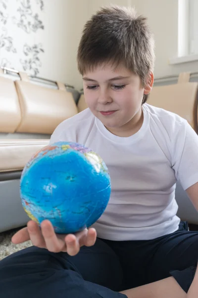 Jongen studeren wereldbol in de kamer — Stockfoto