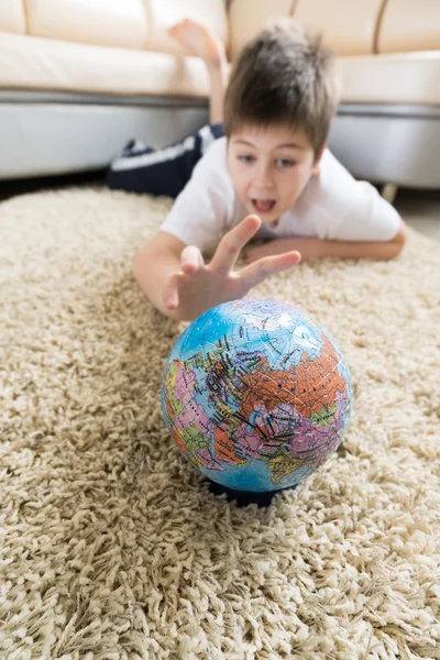 Мальчик изучает глобус в комнате — стоковое фото