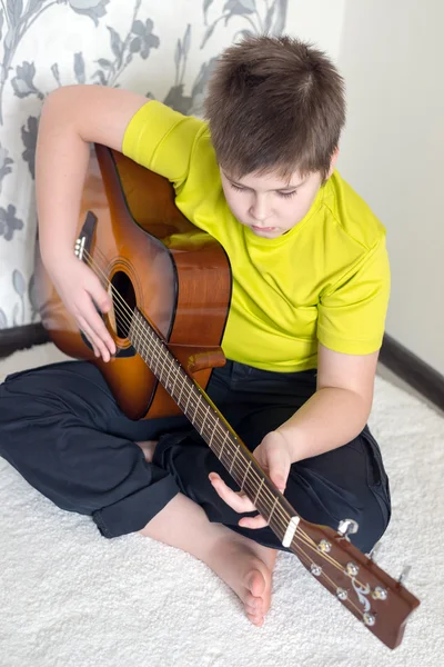 Tonårspojke spelar en akustisk gitarr — Stockfoto