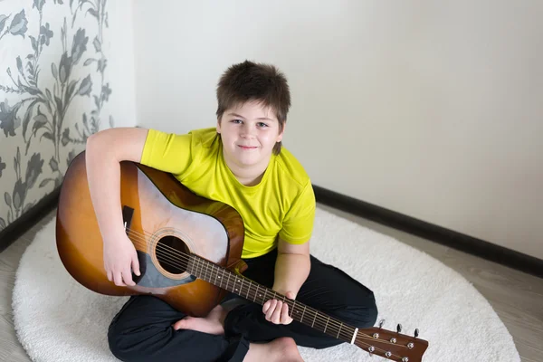 Tonårspojke spelar en akustisk gitarr — Stockfoto