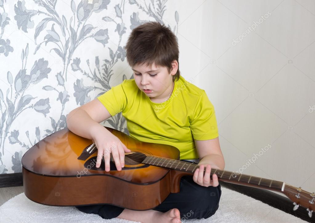 Teenage Boy plays an acoustic guitar