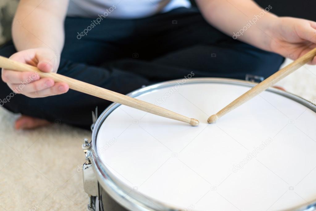 Boy teenager playing drums in  room