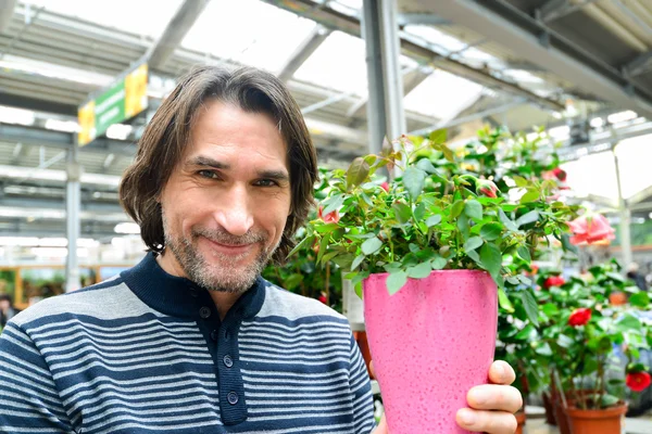 Man holding a flowers working in agreenhouse at garden center — Stock Photo, Image
