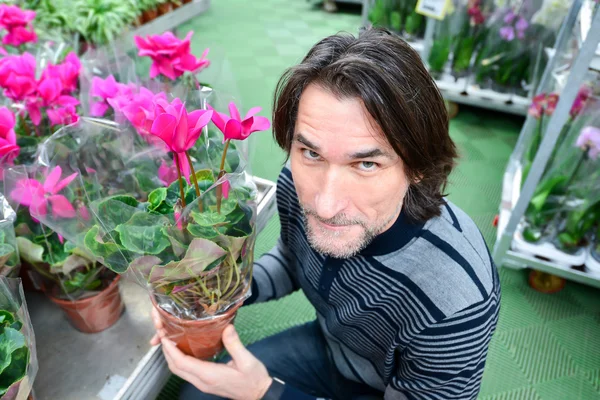 Man holding a flowers working in agreenhouse at garden center — Stock Photo, Image