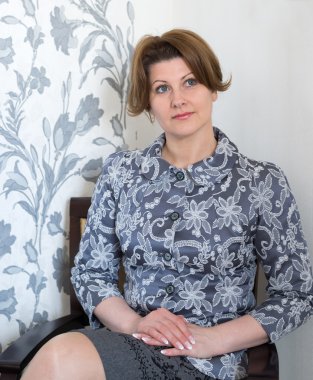 Orta yaşlı kadın sandalyede oturma odasında oturuyordu