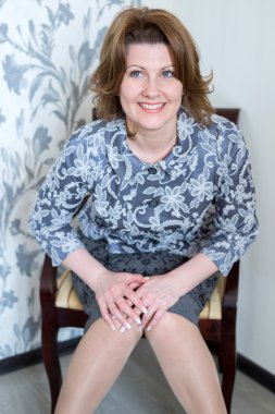 Orta yaşlı kadın sandalyede oturma odasında oturuyordu