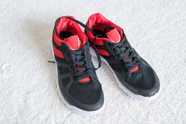 Running shoes met rode trim plat op de vloer — Stockfoto