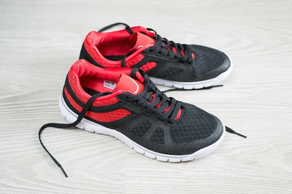 Running shoes met rode trim plat op de vloer — Stockfoto