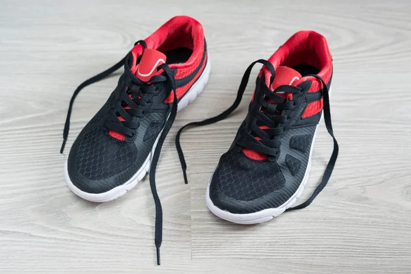 Running shoes met rode trim plat op de vloer — Stockfoto