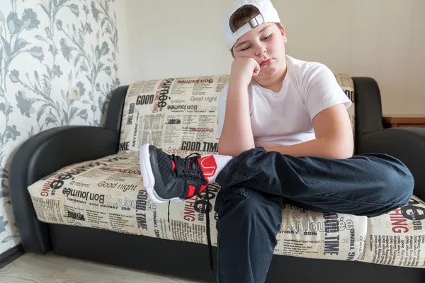Le garçon porte des chaussures de course assis sur un canapé dans la chambre — Photo
