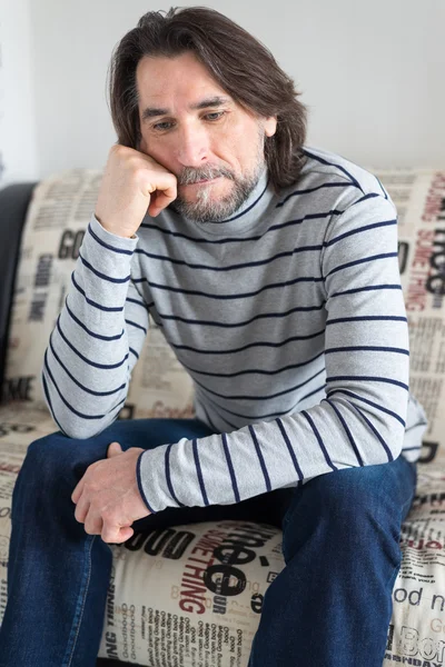 Sad man sitting on a sofa in the room — Stock Photo, Image