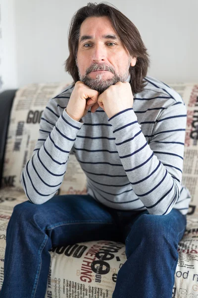 Sad man sitting on a sofa in the room — Stock Photo, Image