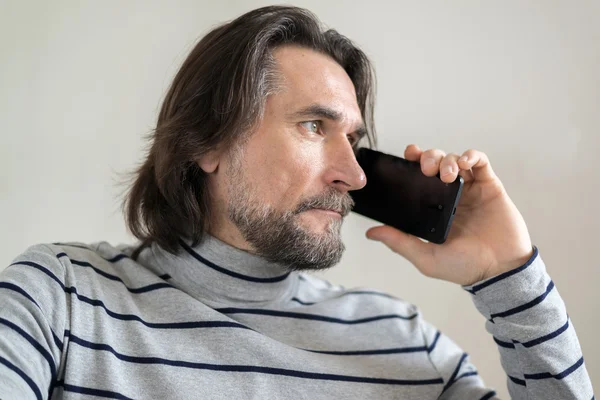 Homem barbudo falando ao telefone na sala de estar — Fotografia de Stock