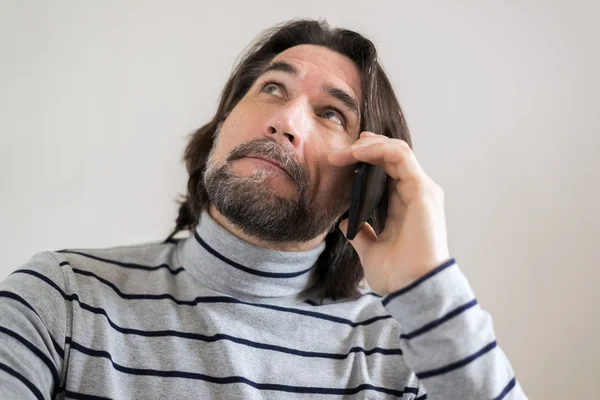 Homem barbudo falando ao telefone na sala de estar — Fotografia de Stock