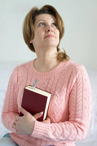 Mujer positiva con un cuaderno y una pluma en la mano — Foto de Stock