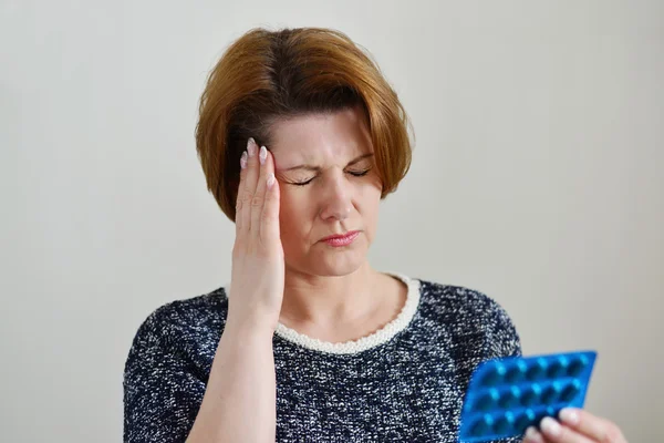 Mujer adulta tomando una pastilla para el dolor de cabeza — Foto de Stock