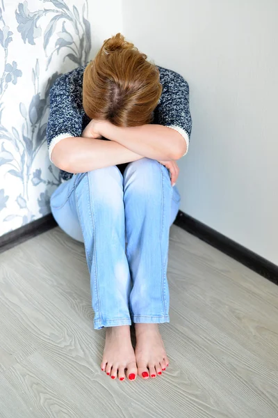 Женщина с депрессией сидит в углу комнаты — стоковое фото