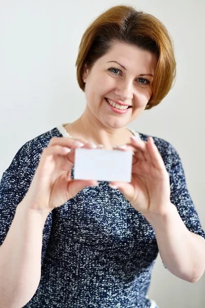 Ενήλικη γυναίκα, κρατώντας μια λευκή κάρτα στο χέρι — Φωτογραφία Αρχείου