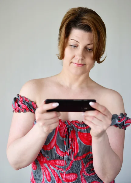 Доросла жінка дивиться на мобільний телефон — стокове фото