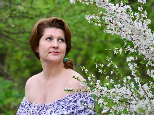 Donna adulta vicino ai fiori di ciliegio — Foto Stock