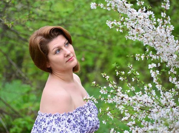 Mujer adulta cerca de las flores de cerezo — Foto de Stock